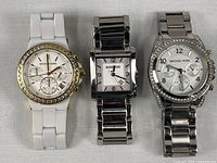 Front view of all three Michael Kors watches showing dial styles and bracelets