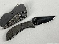 Knife shown open beside closed view highlighting decorative swirl side