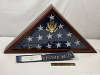 Front view of triangular display case with flag, plaque, streamer