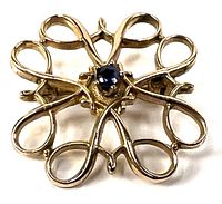 Front view showing gold filigree flower design and central emerald