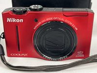 Front view red Nikon Coolpix S8100 camera with lens and case