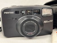 Front view of Pentax IQZoom 140 camera showing lens, flash, viewfinder windows