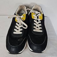 Top view of both sneakers showing lace-up fronts, black mesh uppers and yellow tongue detail
