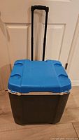 Front view of blue-lid grey Igloo rolling cooler with telescoping handle extended