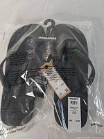 Front view of flip flops in packaging showing brand and size tag