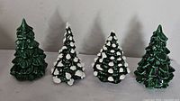 Four small ceramic Christmas trees grouped together