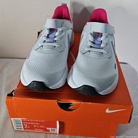 Front view of sneakers on box showing toe shape strap and size label