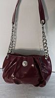 Front view of burgundy Kendall & Kylie purse showing logo medallion and chain strap
