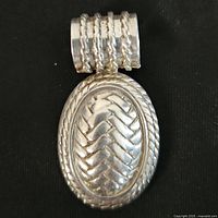 Front view of sterling silver oval pendant showing chevron pattern and rope edge