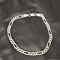 Full view of sterling silver Figaro bracelet on fabric background