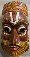 Frontal view of entire mask showing carved features and paint