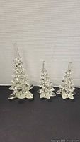 Three clear glass Christmas tree figurines in graduated sizes