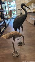both metal heron statues side by side