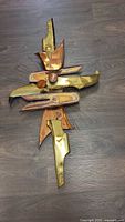 Full view of brass and copper abstract wall sculpture on floor