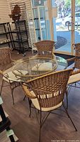 Round glass table with four wicker chairs full view