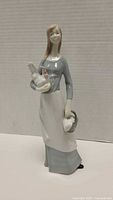Front view of Nao porcelain woman figurine holding chicken and basket