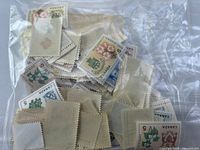 Bag of loose Canadian 5¢ stamps showing assorted designs, back sides visible