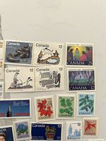Group view of assorted Canada stamps showing Inuit art, canoe, Christmas, maple leaf and pine designs