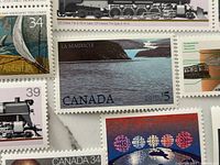 Close-up of several 1983 Canadian mint stamps including $5 La Mauricie and 34¢ locomotive