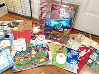 Overview of assorted Christmas gift bags and tags spread on floor