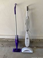 Front view of both mops standing upright – Luna Plus steam mop on right, Swiffer WetJet on left