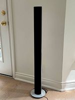 Front view of one BeoLab 8000 speaker showing black grille and circular base