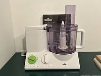 Front view of Braun TributeCollection food processor with bowl, lid, spindle and booklet