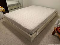 Three-quarter view of cream wood queen platform bed with mattress