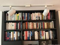 Full view of three-shelf bookcase filled with assorted hardcover and softcover books
