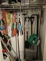 Overall view showing hanging extension cords, hedge shears, rakes and shovels