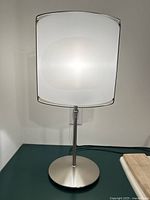Front view of brushed metal lamp with lit frosted glass shade