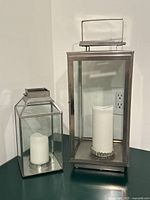 Two stainless steel glass lanterns with candles on tabletop