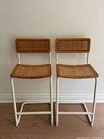 Pair of matching rattan and white metal bar stools front view