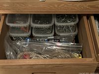 Drawer with six clear tubs of screws and hardware plus rope in zip bags