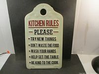 Front view of the metal kitchen rules sign showing text and shape