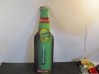 Front view of beer-bottle shaped metal thermometer