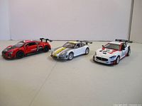 Three 1:32 scale die-cast sport cars grouped