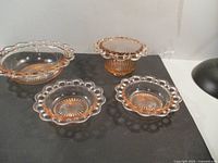 Four pink Depression glass pieces with lace edge rims