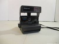 Front view of Polaroid OneStep Close-Up camera showing flash, lens, branding and strap