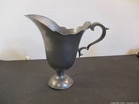 Side view of pewter jug showing handle and pedestal base