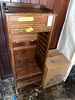 Front view of cabinet with shutter door open showing interior drawer slots and lower drawer
