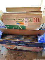 Open top of first case showing packaged flattened banker boxes and lids