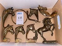 All items in box: five horse head hooks, brass towel ring bracket visible, unicorn figurine
