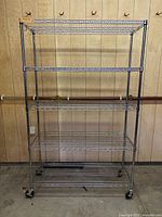 Full front view of empty chrome rack showing five shelves and casters