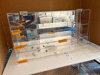 Front view of acrylic display case showing shelves, mirrored back, hardware packets