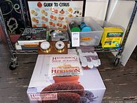 Entire lot on cart showing hedgehog scraper box, barometer plaque, plant vitamin boxes, pump, pond cleaner, scouring stick