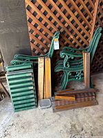 Overall lot: two cast iron bench ends, stacked green slats, brown slats, hardware tray