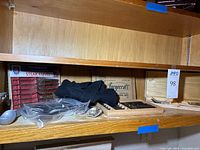Shelf view showing boxed Forgecraft and Regent Sheffield steak knife sets, loose flatware, apron, wood tray