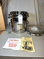 Complete stainless steam juicer set stacked with lid wrapped and literature displayed