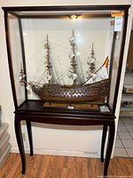 Full view of model ship inside glass display case on stand